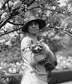 Coolidge wearing a large hat and holding a raccoon