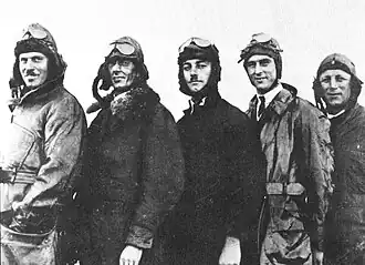 Informal three-quarter portrait of five men in flying suits and goggles
