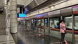 The station platform is separated from an incoming train by the platform screen doors.