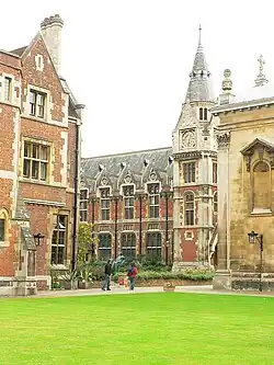 A green lawn with a red-brick building and a limestone chapel behind