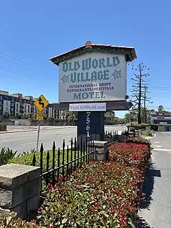 Entrance sign reading "Old World Village" with red roof tiles