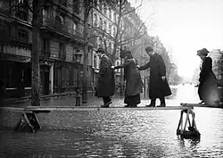 Pedestrians traversing planks over the floodwaters