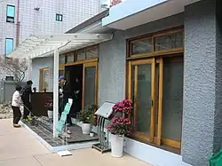 Visitors to the exhibit removing their shoes before entering the house (2016)