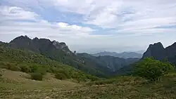 A photo of sprawling mountains covered in short bushes and shrubs at daytime