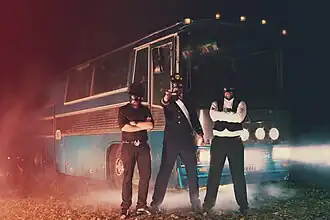 The Märvel trio of the Vicar (left), the King (center), and Burgher (right) in front of their tour bus.