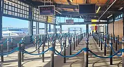 A picture of the interior of the Pier 50 passenger ferry terminal. This image shows the lines set up in front of the ramp that leads onto the ferries, and the Doc Maynard visible through the windows.