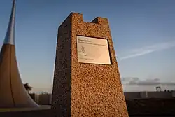 A metal plaque with a mathematical formula on a granite pillar