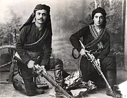 Two men in traditional Pontic clothing pose with guns.