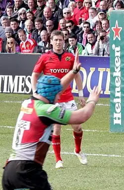 Ronan O'Gara standing in the field with Munster, near a Heineken-sponsored post pad, in 2013