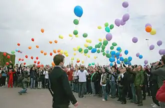Large group of people releasing multicolored balloons