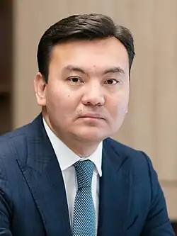 Headshot of Rauan Kenzhekhanuly in an office. He is a middle-aged man wearing a morning suit.