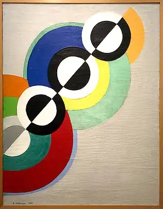Abstract painting of concentric circles arranged along a diagonal axis. The axis bisects each circle, and each half is a different color.