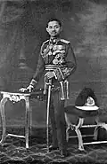 King Prajadhipok in the scarlet uniform, with the old style helmet to the right in the photograph
