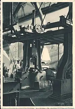 Vieille photographie montrant un marteau-pilon dans un atelier.