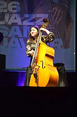 Noriko Ueda plucks a double bass on a stage at a festival.