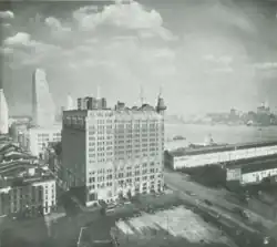 A multi story building seen from above with a river visible behind it