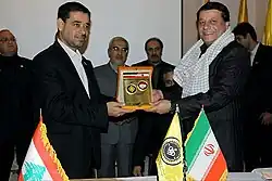 Two smiling men holding a golden plaque together