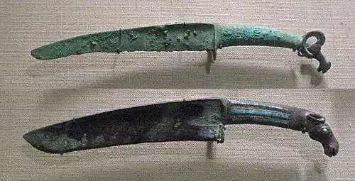 Shang dynasty curved bronze knives with turquoise inlays and animal pommel. 12th–11th centuries BC. Such knives may be the result of contacts with northern people.[87]