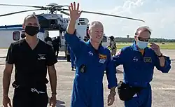 Douglas Hurley waves to onlookers as he boards a plane at Naval Air Station Pensacola.