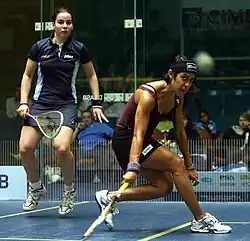 A teammate in a dark blue uniform jumps up while David passes the ball to her.
