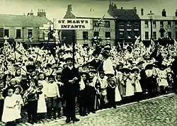 Group of children holding union flags lined up in a road.