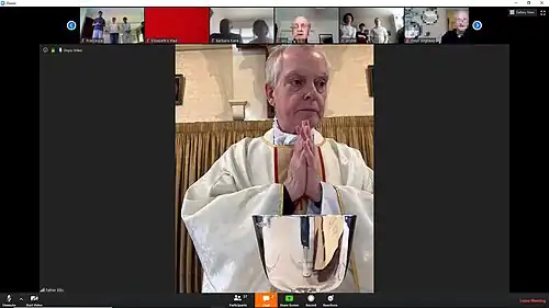 St. Thomas Aquinas Church in a ZOOM session with Fr. Robert Ellis during the COVID-19 lockdown. The priest is shown on the main screen, with his hands together during prayer.