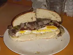 A steak and egg sandwich with bacon and cheddar cheese