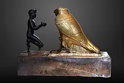 Taharqa offering wine jars to Falcon-god Hemen;[63] 690–664 BC; bronze, greywacke, gold and wood; length: 26 cm, height: 19.7 cm, width: 10.3 cm; Louvre