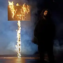 J. Cole walking away from a burning basketball hoop