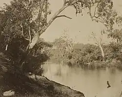 Dirt road in foreground with sailing ships at wharf in background
