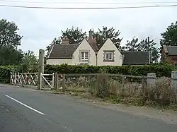 fac-on view of the station building with its two dormer windows. At some point since conversion to a house it has been whitewashed. Just visible on the right of the house is the red brick gable of the former goods shed