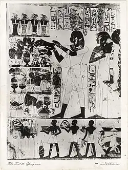Wall painting scene from the transverse chamber, east wing. In the scene, the deceased and his wife Wadjrenpet (behind her is a third person - their son, not visible here) make offerings to honour Amun-Ra and Osiris. At present, the wall is partially ruined, in contrast to the state of preservation at the time of the photograph[5] (around 1930s).