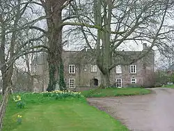 Photograph of a large country house surrounded by trees