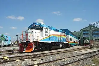A pair of DMUs trailing behind EMD GP49 engine 813 in Hialeah Railyard