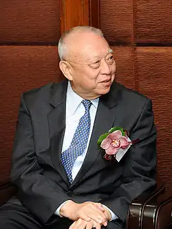 Portrait of Tung Chee-hwa wearing a black suit and a blue tie