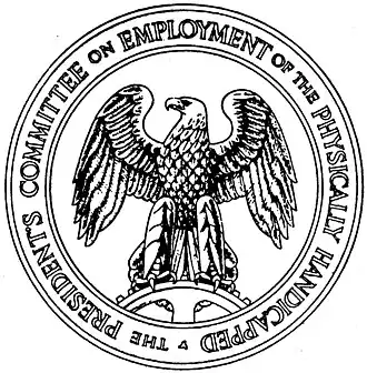 A round seal with the words "The President's Committee on Employment of the Physically Handicapped" around the edge. In the center is an eagle standing on a spur gear and facing to its right.
