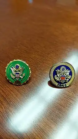 A small pin held onto an article of clothing with a Congressional seal on it
