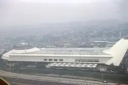 A foggy aerial view of city shows a long, white, low-rise building with the words General Motors on its roof.