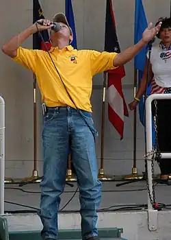 Singer Neal McCoy singing into a microphone while looking upward.