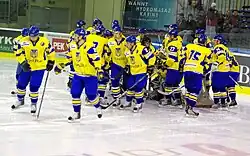 Hockey players in blue and gold uniforms in a group around a hockey net