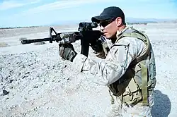 A US Navy SEAL aims his M4 carbine with an attached LA-5C/PEQ as part of the SOPMOD Kit.