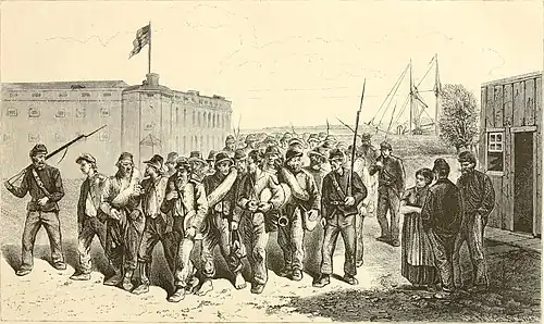 A lithograph of a large column of soldiers without weapons in disorderly dress marching outside a large stone fort being guarded by a few soldiers in dark uniforms holding rifles