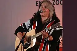 Vivir Quintana singing and performing with a guitar