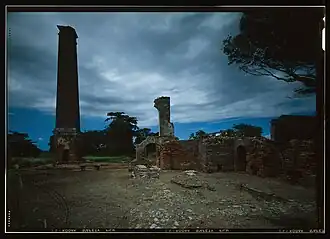 View of sugar mill ruins showing chimney and masonry base of steam engine and cane mill at right, ca. 1968
