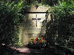 A gravestone surrounded by vegetation. On it are the four names and dates, with August and Annie at the top on either side of a large cross. Below the cross Werner and Elisabeth are listed.