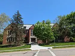 Brick building with trees in front and a bright blue sky.