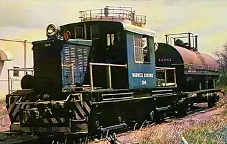 A blue locomotive marked "Warwick Railway" and the number 104 pulling a single tank car on a curved section of track.