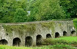 A low, stone arch bridge with eight consecutive arches in view.