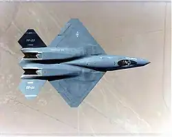 Top view of black jet aircraft, showing diamond wings, engine nozzles with exhaust trenches, and two-piece tail. The separation between the forward fuselage and engine nacelles is apparent.