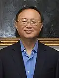 a smiling man with a cropped haircut, wearing glasses and a blue shirt